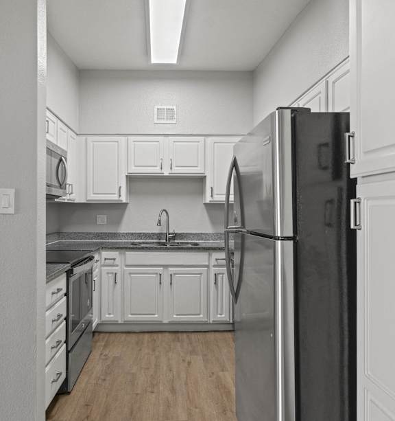 A kitchen with white cabinets and a black refrigerator.