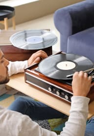 a man listening to a record player on a coffee table at  The Hallon Apartments, Hopkins,MN