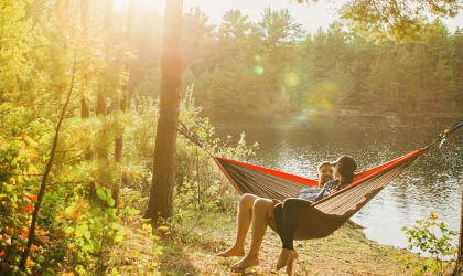 a couple relaxing in a hammock by a lake