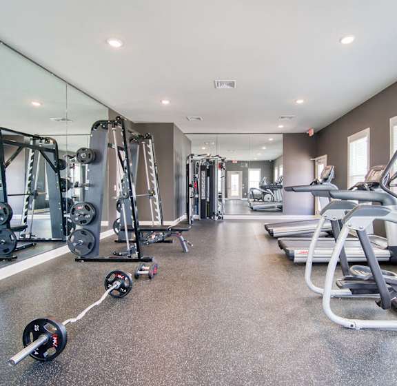 A spacious gym with a variety of equipment including treadmills, weight machines, and dumbbells.