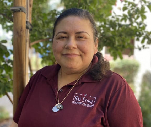 a woman in a red shirt standing in front of a tree