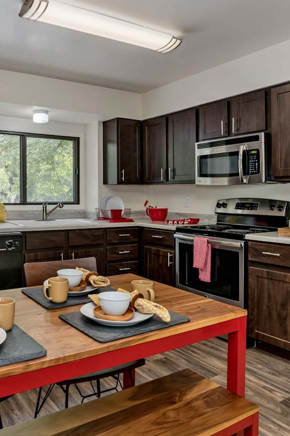 A modern kitchen with a wooden table set for two.