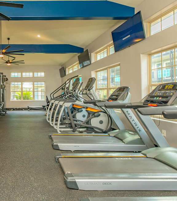 A gym with treadmills, exercise bikes, and a fan. at The Cove at State Street Apartments, Baton Rouge, LA, 70802