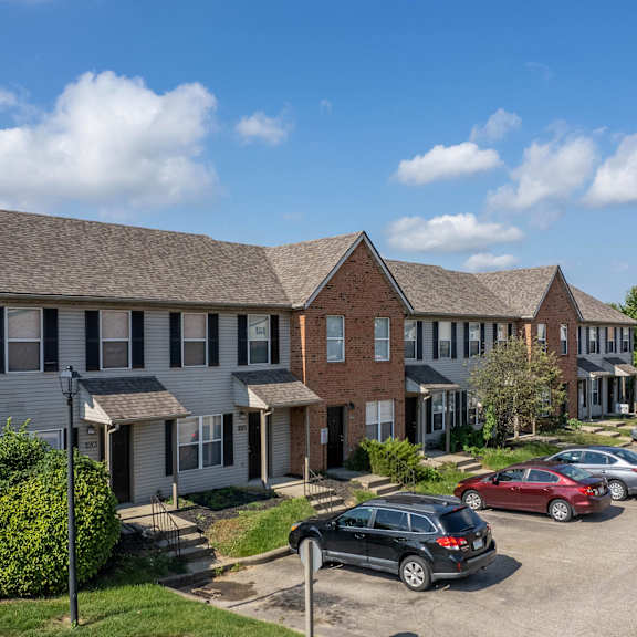 A row of houses with cars parked in front.