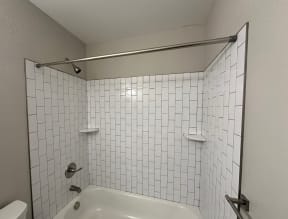 a white tiled bathroom with a tub and a sink