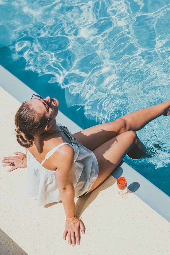 a woman is sitting on the edge of a pool