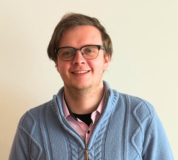 A man wearing glasses and a blue cardigan.