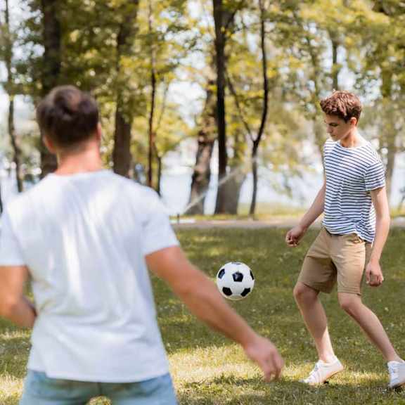 Two people playing soccer in a park.