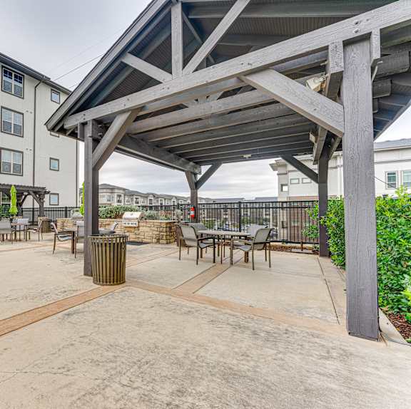 A patio area with a table and chairs under a roof.