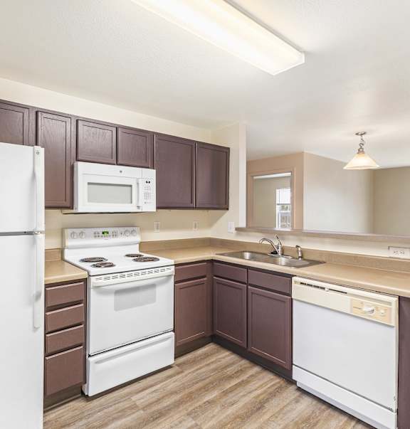 A kitchen with brown cabinets and white appliances.