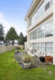 the back of a house with a yard with chairs and a fence