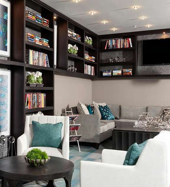A living room with a bookshelf filled with books and a flat screen TV mounted on the wall.